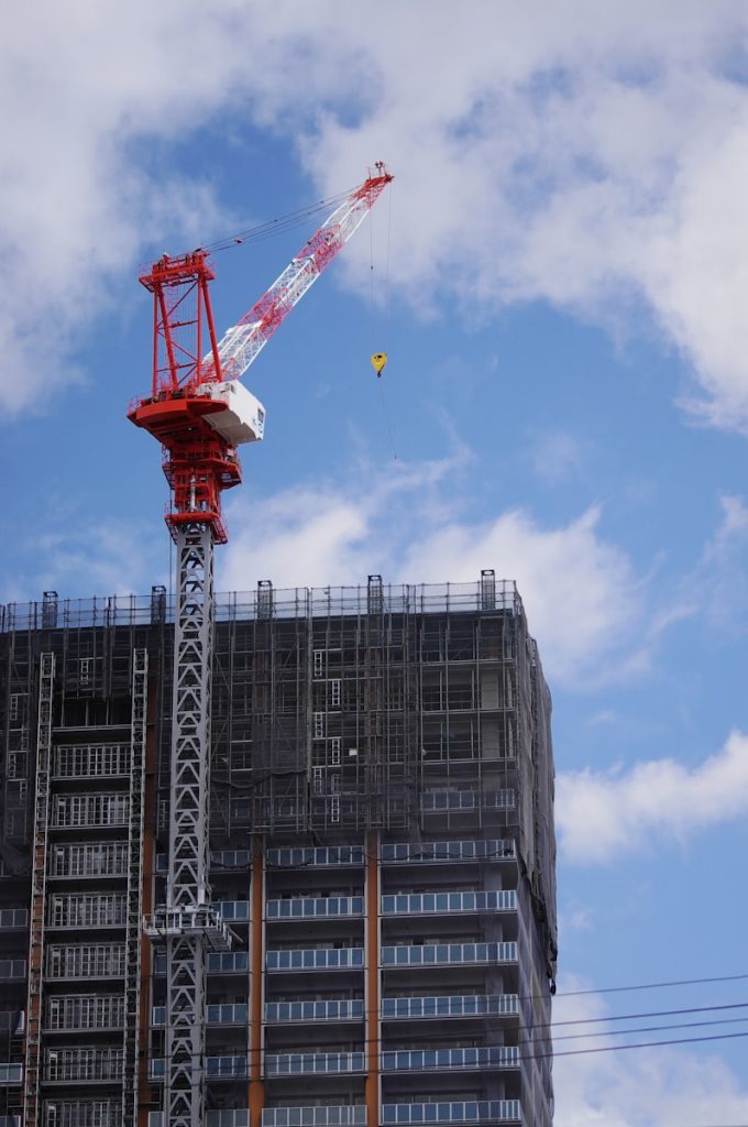 red crane near gray building during daytime Photo by taichi nakamura